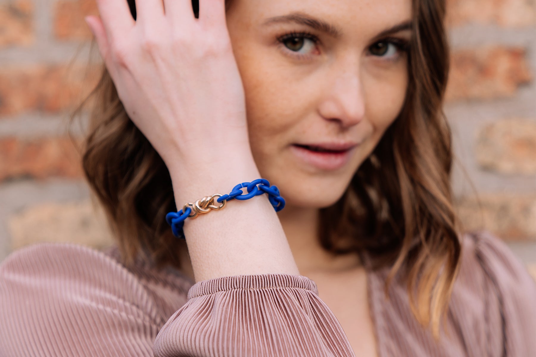 Model wearing a cobalt blue bracelet with a bronze link