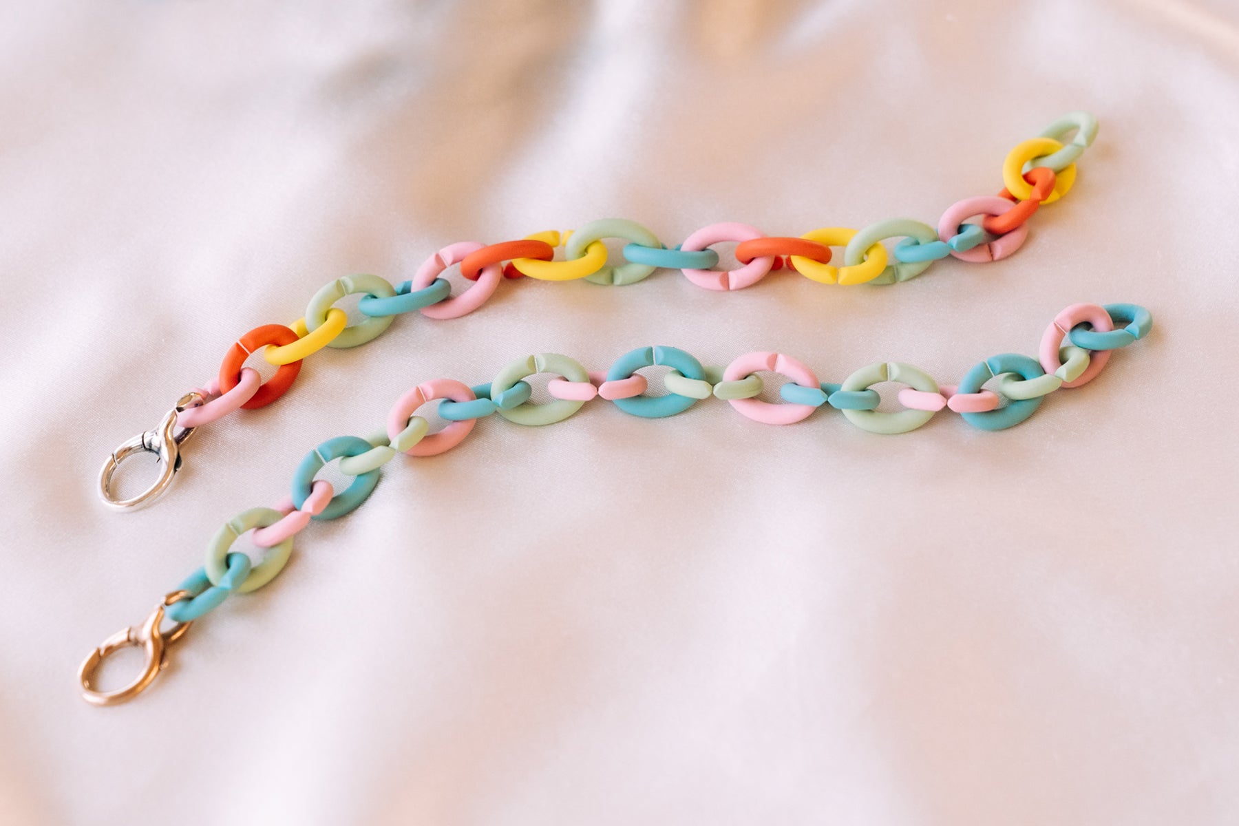 Pastel bracelets laying on white silk